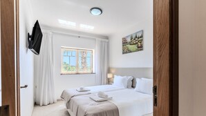 Una habitación de hotel con una cama, una ventana con cortinas, un cuadro en la pared y un televisor de pantalla plana montado en la pared.