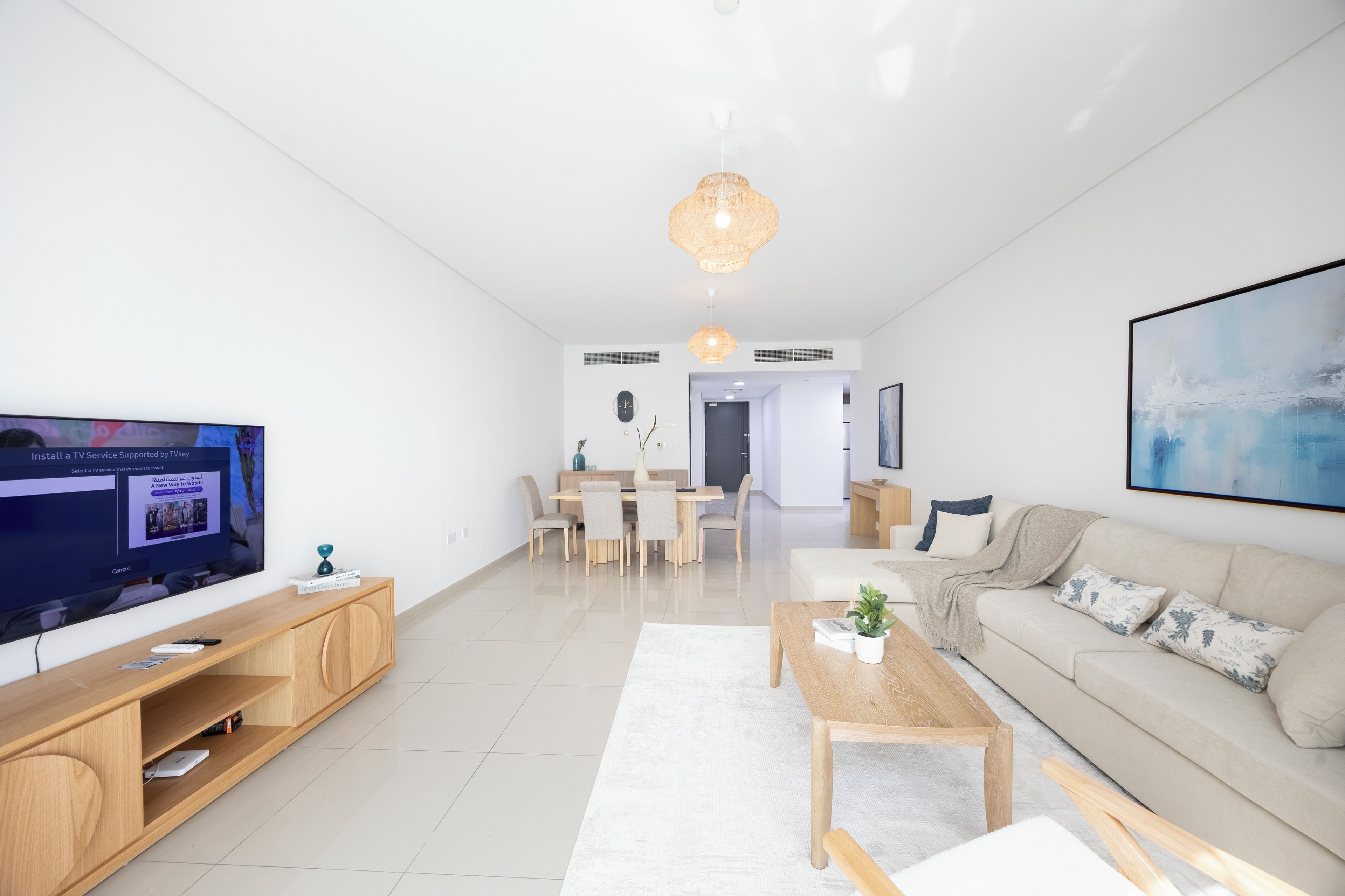 A modern living room with a TV, wooden furniture, a sofa, and a dining area.