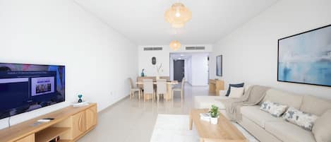 Una sala de estar moderna con televisor, muebles de madera, un sofá y un comedor.
