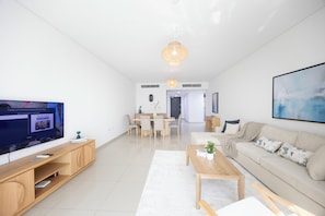 Uma sala de estar moderna com TV, móveis de madeira, um sofá e um espaço de jantar.