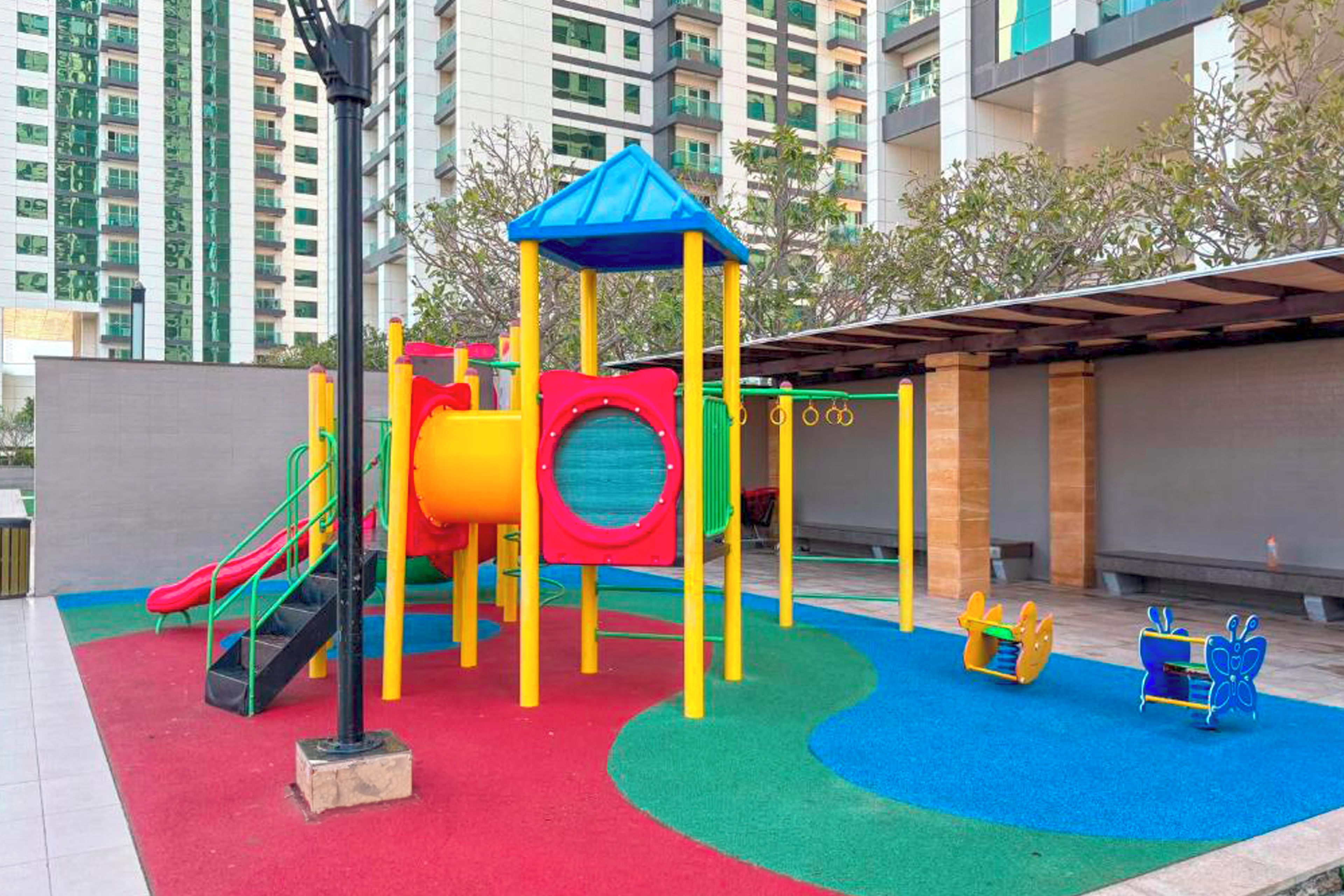 Une aire de jeux avec un toboggan, des structures d’escalade et un espace de jeux couvert.