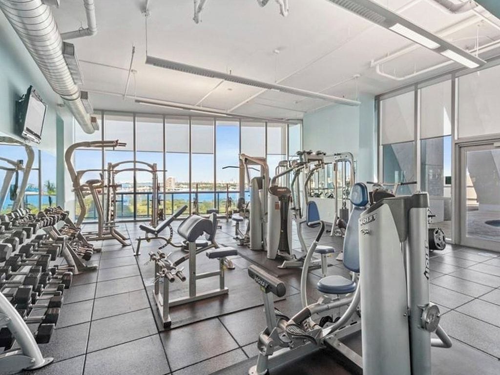 A gym with various exercise equipment, large windows, and a view of the city.