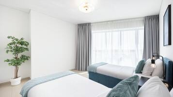 Une chambre d’hôtel avec deux lits, une plante en pot et une vue sur l’extérieur.