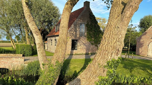 A brick house with a red roof, surrounded by trees and a small pond. - Holiday home Bellefleur (Houtem Veurne)