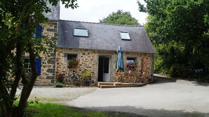 A stone building with a sloped roof, a door, and a small porch area.