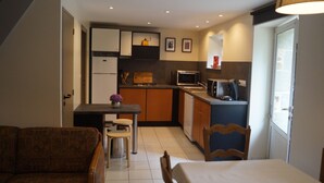 A compact kitchen with a dining area, a sofa, and a window.