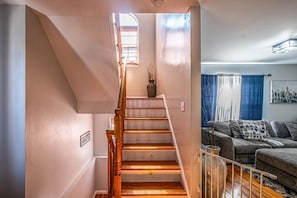 A staircase leading to a living area with a sofa and a painting. - NJNY Retreat - Newark (Newark)