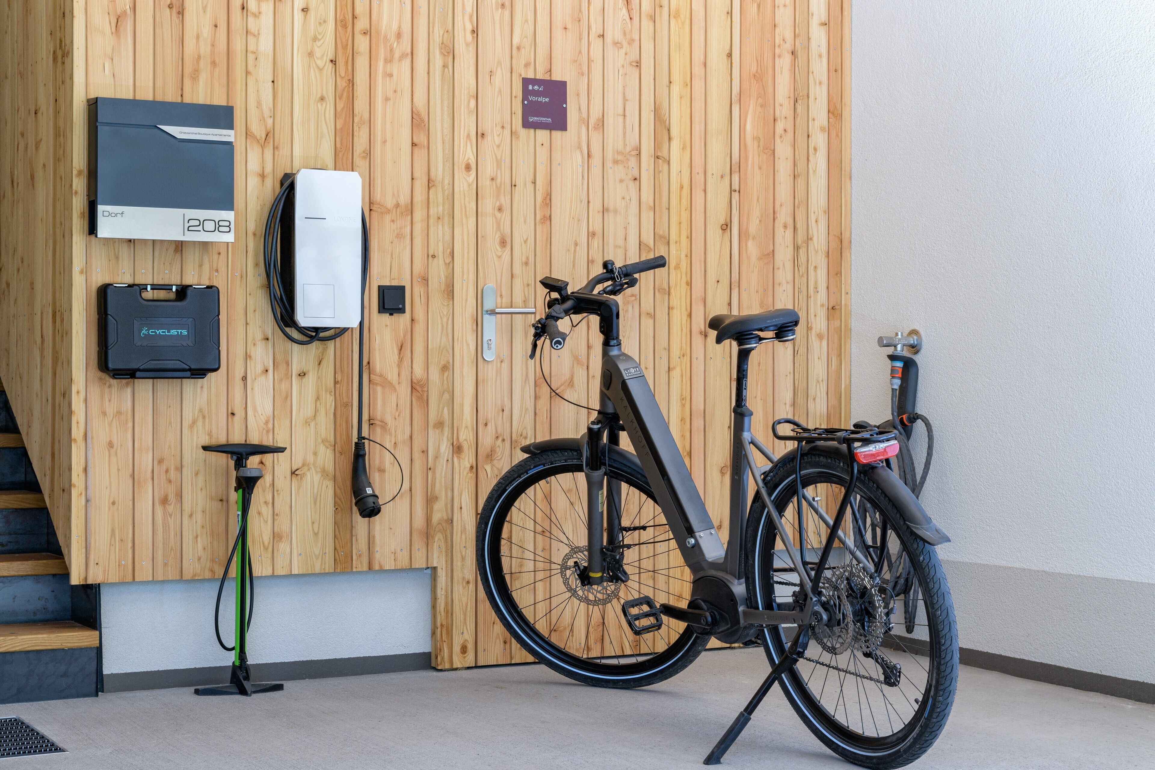 Ein Zimmer mit Holzwand, einem Fahrrad, einer Ladestation und einer Steckdose.