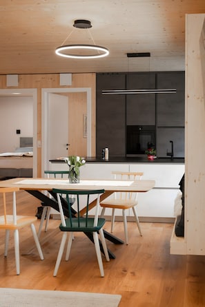 Een moderne keuken met houten vloeren, een eettafel met stoelen en hanglampen.