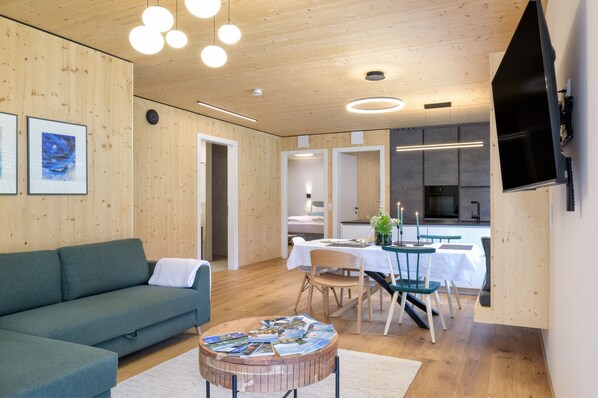 Un salon moderne comprenant un canapé, une table à manger, des chaises et un téléviseur fixé au mur.