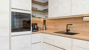 A modern kitchen with a built-in oven, a coffee maker, and a sink. - Seeau Apartment – Apartment with Terrace and Garden (Hollenstein an der Ybbs)