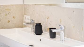 Une salle de bain avec un lavabo blanc, deux robinets et un miroir.