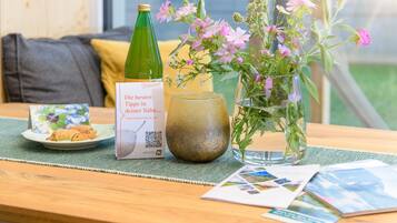 Een tafel met een fles, een glas, een bord eten, een boekje en een vaas met bloemen.