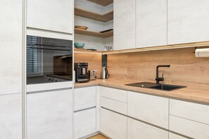 A modern kitchen with a built-in oven, a coffee maker, and a sink.