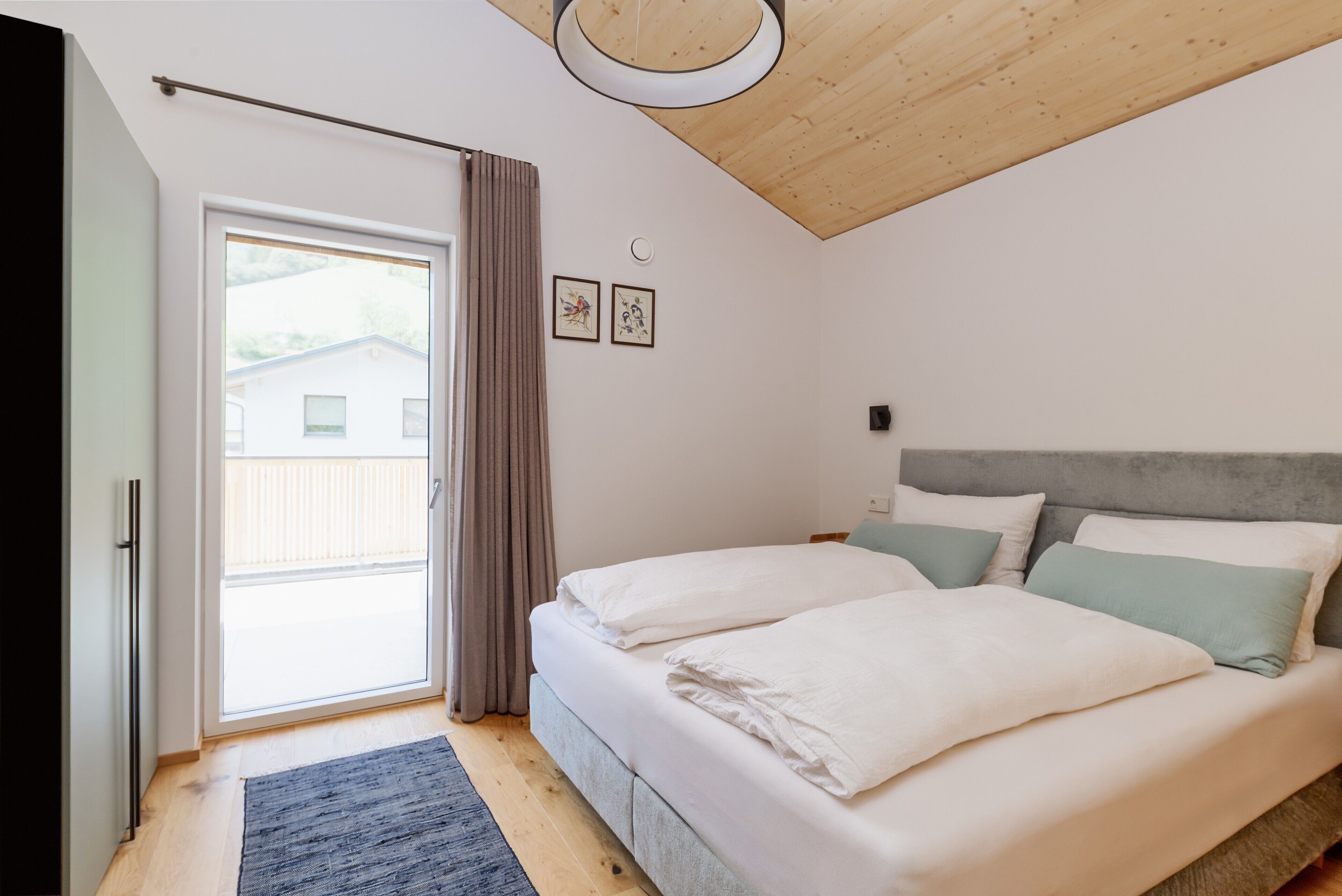 A bedroom with a bed, a window with curtains, a ceiling light, and a wall-mounted picture.
