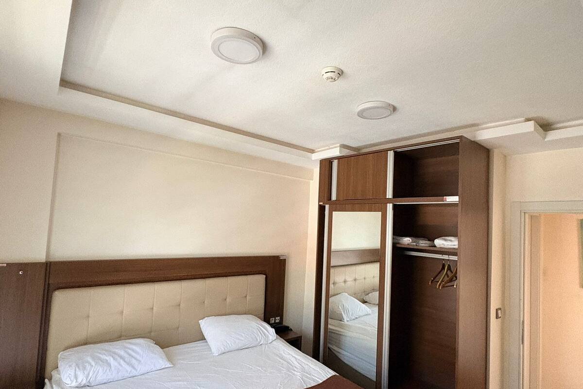 Hotellihuone, jossa on sänky, vaatekaappi ja peili.