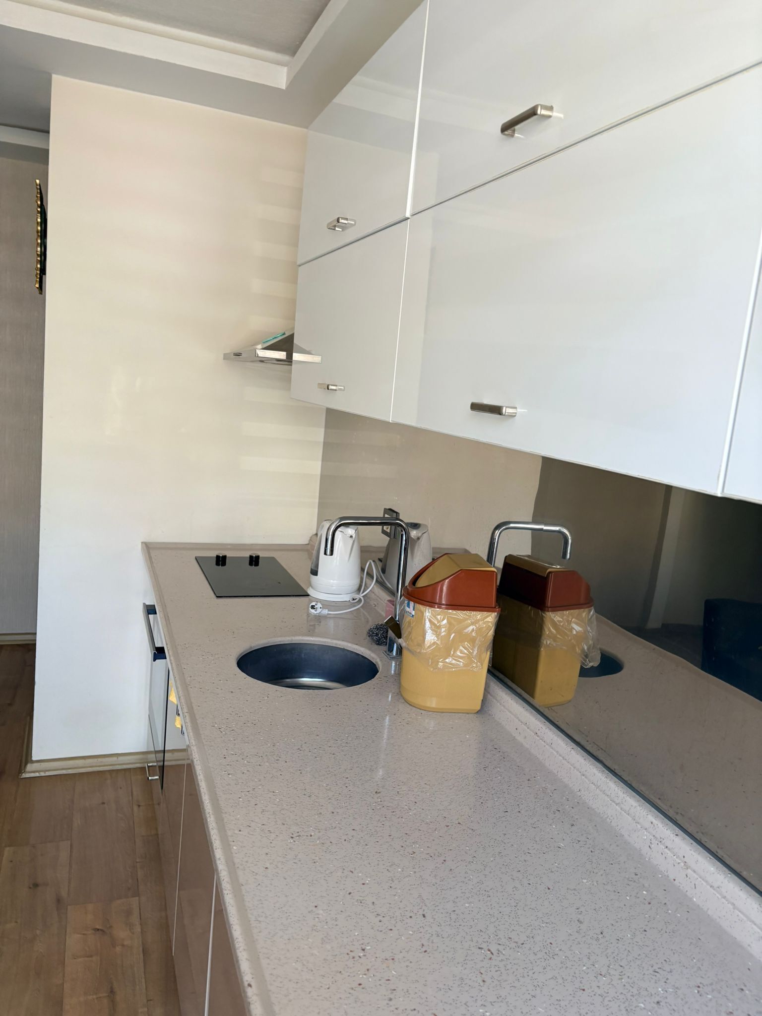 Una cocina moderna con armarios blancos, un lavamanos de acero inoxidable y una encimera.