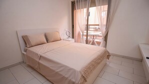 Ein Schlafzimmer mit Bett, Nachttisch, Spiegel und Blick auf eine Terrasse.