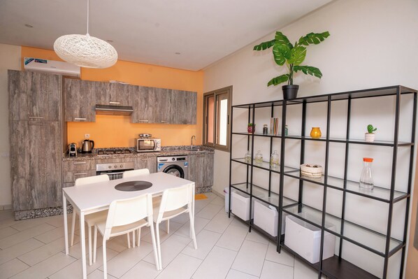 A modern kitchen with a dining area, built-in appliances, and a potted plant.