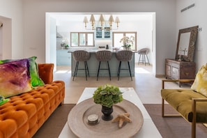 Ein modernes Wohnzimmer mit einer Couch, einem Couchtisch mit Pflanze und einem Essbereich mit Barhocker.
