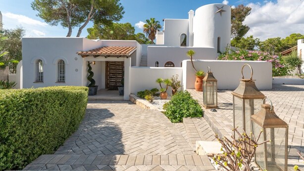A white building with a tiled roof, arched windows, and a spiral staircase leading to a wooden door. - Exclusive Mediterranean Villa with Private Pool in Cala d'Or (Santanyí)