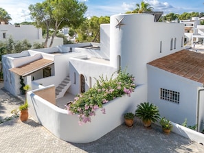 Ein modernes Gebäude mit einer geschwungenen Fassade, einer kleinen Treppe und Topfpflanzen.