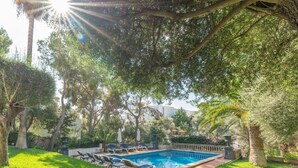 A swimming pool with lounge chairs, surrounded by lush greenery and trees. - Exclusive Mediterranean Villa with Private Pool in Cala d'Or (Santanyí)