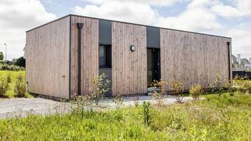 Un bâtiment moderne en bois, doté d’un toit plat, de grandes fenêtres et d’une porte.
