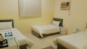 Habitación de hotel con dos camas, una mesita de noche con botellas de agua, un calentador y un tapete estampado.