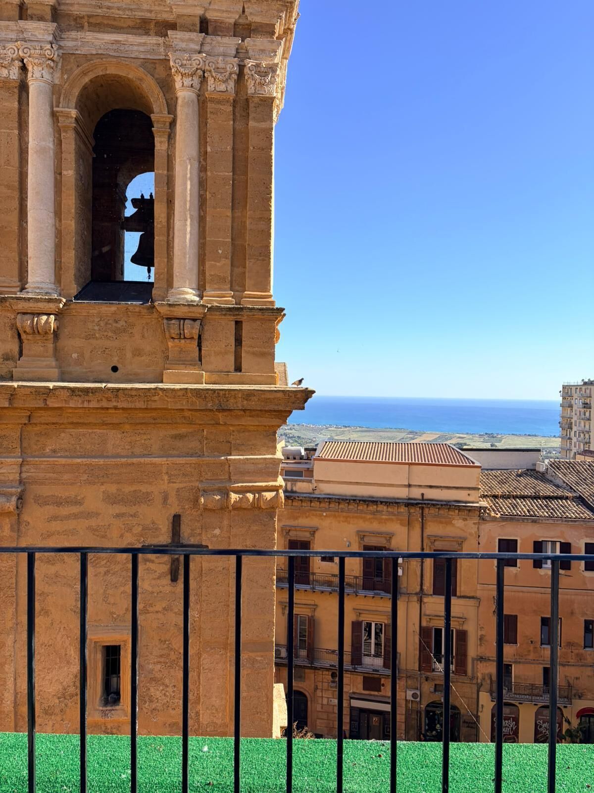 A historic building with a bell tower, a clear view of the sea, and traditional architecture.