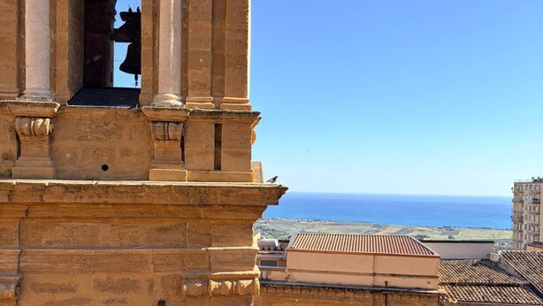 Un edificio histórico con una torre de campanas, vistas despejadas al mar y arquitectura tradicional.