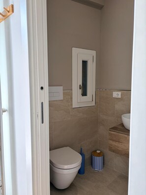 Un bagno con il water, un lavandino, uno specchio e una porta.