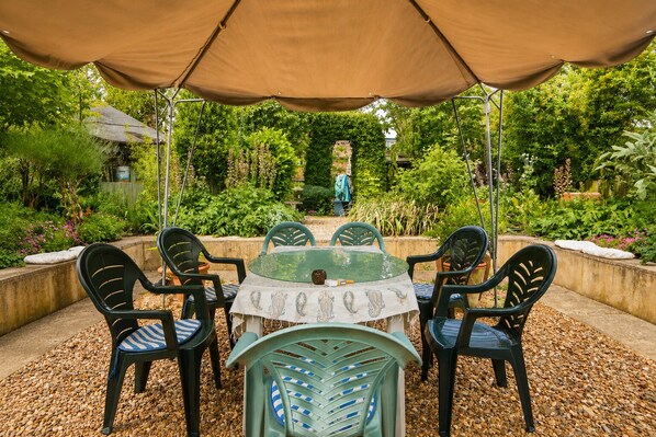 Eine Gartenpatio mit einem runden Tisch und Stühlen, umgeben von einem Garten.