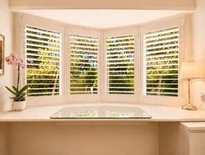 Ein Erker mit vielen Glasscheiben, eine Topforchidee und eine Lampe auf einer weißen Arbeitsplatte.