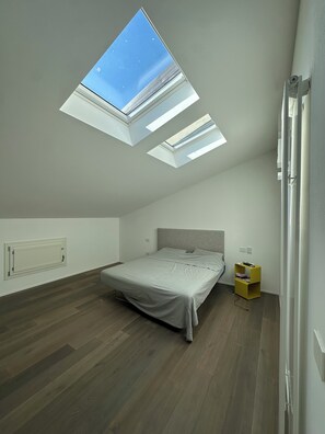 Ein Schlafzimmer mit Dachfenster, einem Bett, einem Nachttisch und einem Beistelltisch.