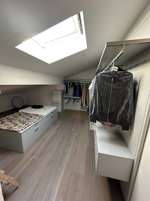 Een slaapkamer met dakraam, een bed, een kledingkast en een inloopkast.