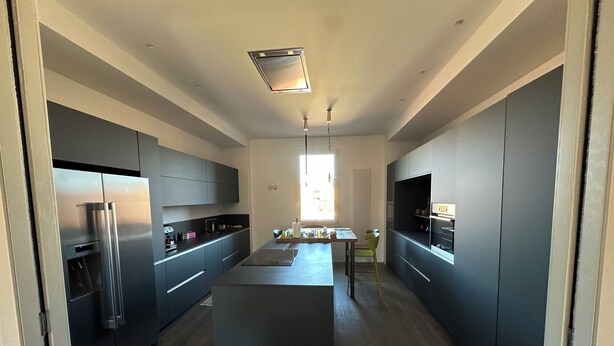 A modern kitchen with a central island, built-in appliances, and a large window providing natural light. - The Loft – Designer Apartment in Castel San Pietro Terme (Castel San Pietro Terme)