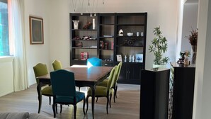 A modern living room with a sofa, dining table, chairs, and a black entertainment unit. - The Loft – Designer Apartment in Castel San Pietro Terme (Castel San Pietro Terme)