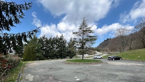 Ein Parkplatz mit Autos, umgeben von Bäumen und blauem Himmel.