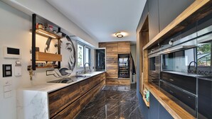 Eine moderne Küche mit Marmorarbeitsplatte, Holzschränken und Blick ins Freie.
