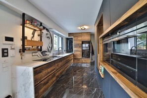 Eine moderne Küche mit Marmorarbeitsplatte, Holzschränken und Blick ins Freie.