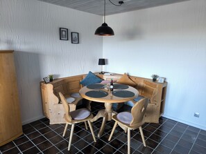 Un coin repas accueillant avec une table ronde en bois, des chaises rembourrées et un luminaire suspendu.
