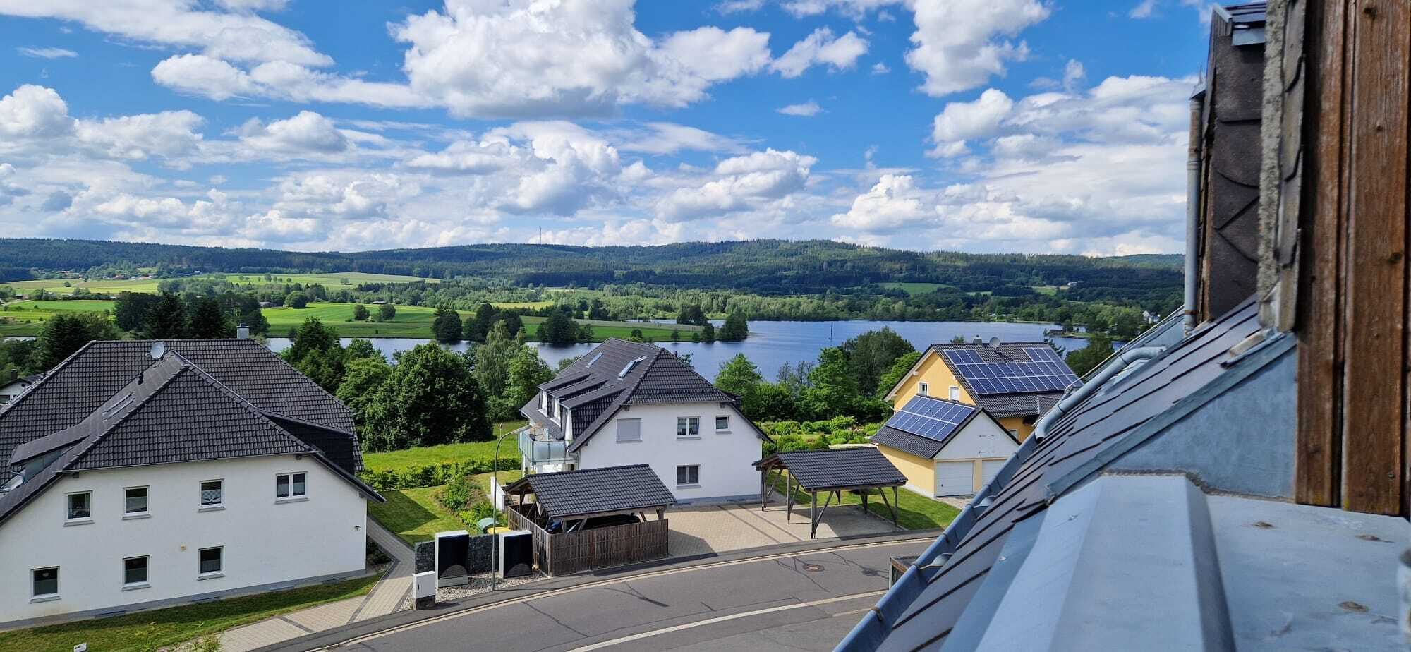 Et boligområde med huse, en vej og en sø i baggrunden.