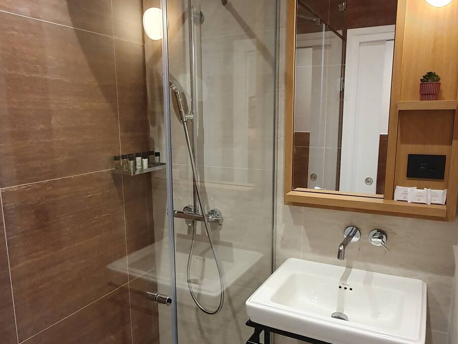 A modern bathroom with a glass-enclosed shower, a white sink, and a wooden vanity.