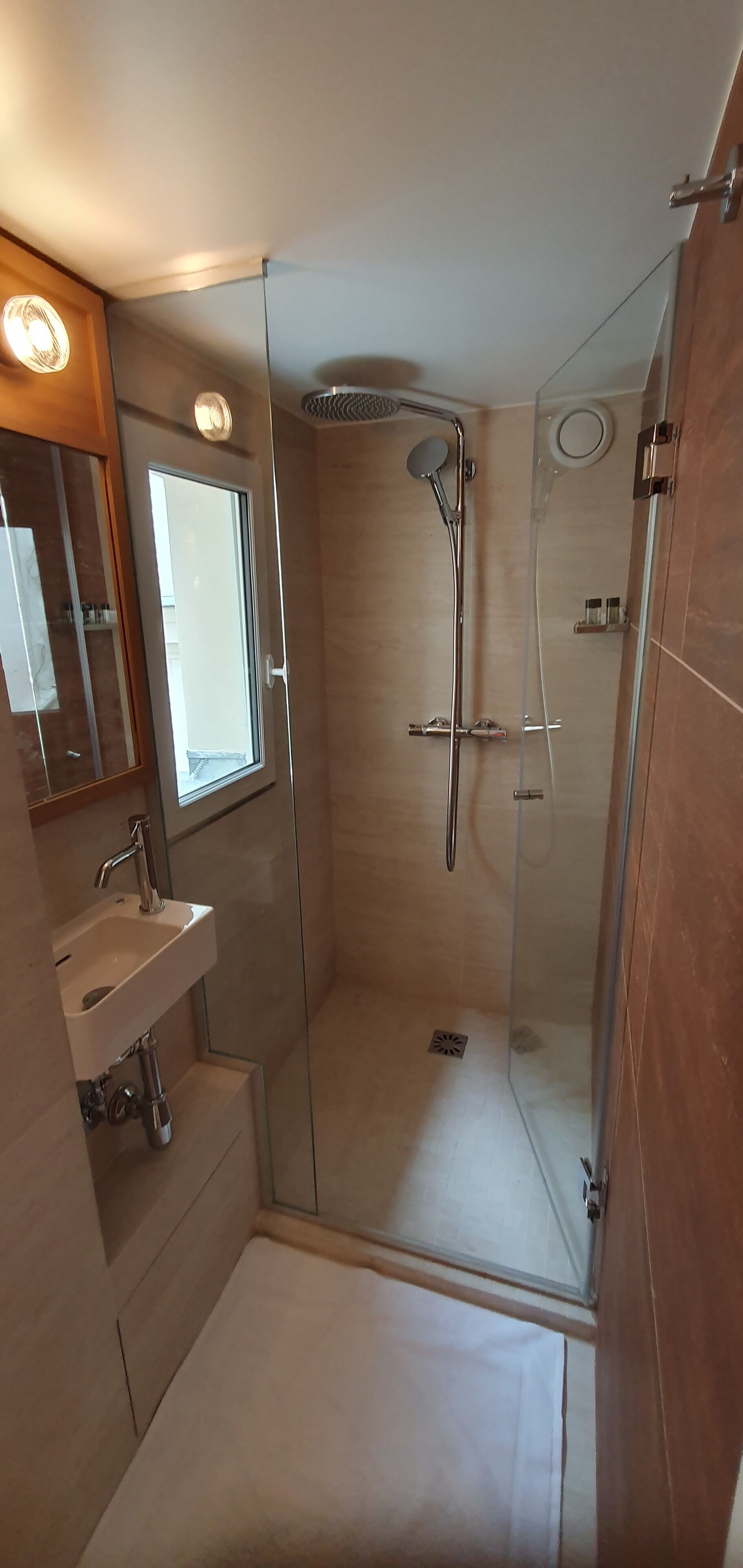 Une salle de bain moderne avec une douche à parois de verre, un lavabo et un miroir.