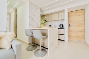A modern kitchen with marble backsplash, a coffee machine, and a wooden door. - Ivory Tide Coastal Apt • Ocean View • Beach WiFi (Cartagena)