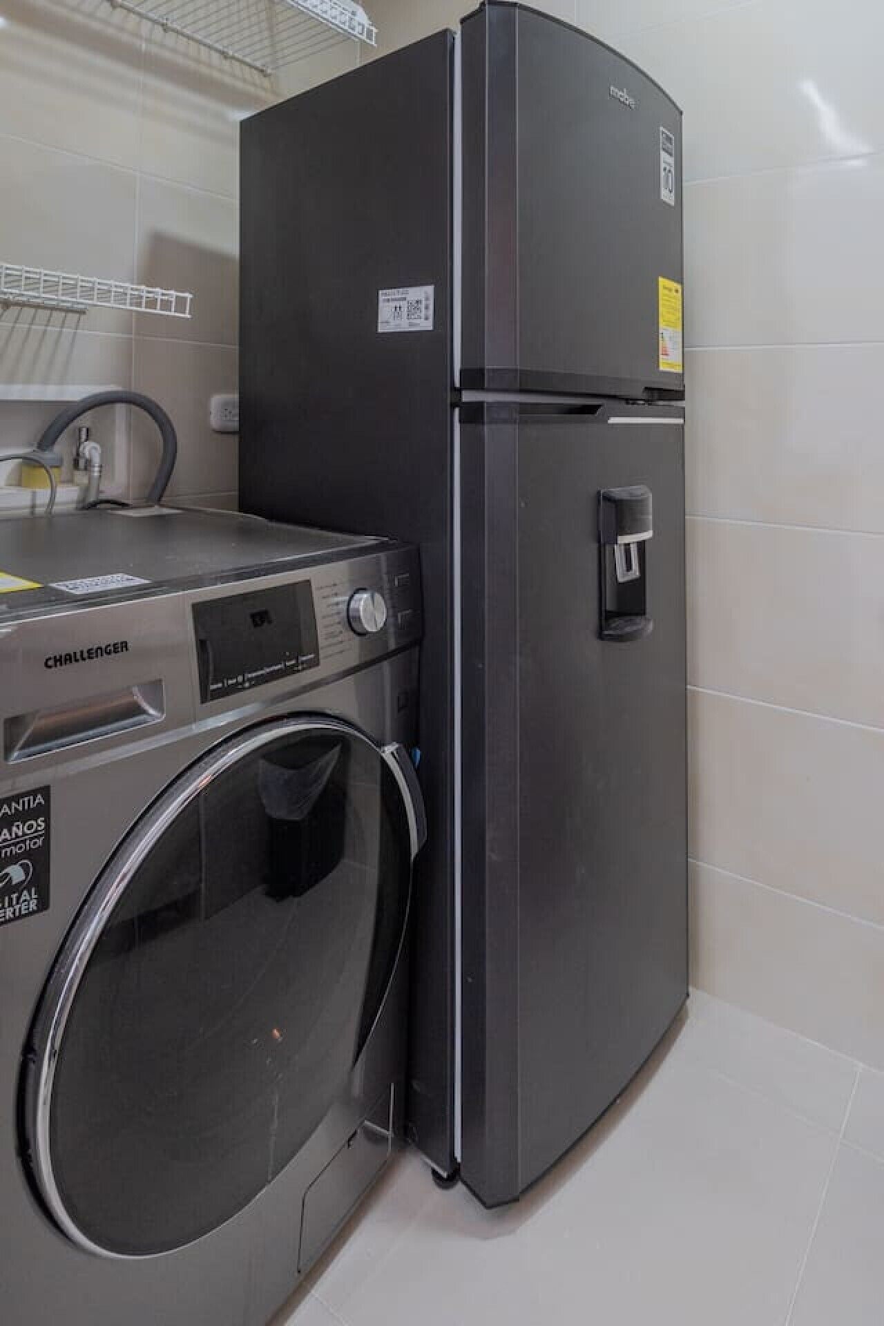 Une cuisine compacte équipée d’un réfrigérateur en acier inoxydable, d’un lave-linge et d’un évier.