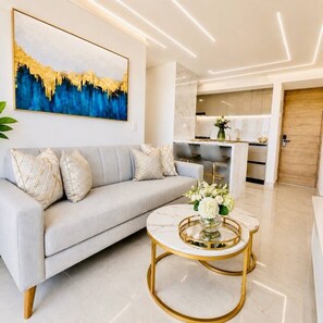 A modern living room with a sofa, a coffee table, and a painting on the wall. - Ivory Tide Coastal Apt • Ocean View • Beach WiFi (Cartagena)
