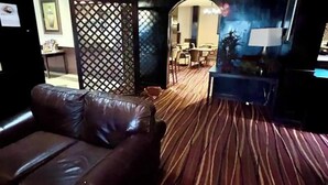A room with a brown leather sofa, a patterned carpet, a dining area with chairs and a table, and a wall with a decorative panel. - Cozy 1-bedroom bed & breakfast in wonderful Albany with AC (Albany)