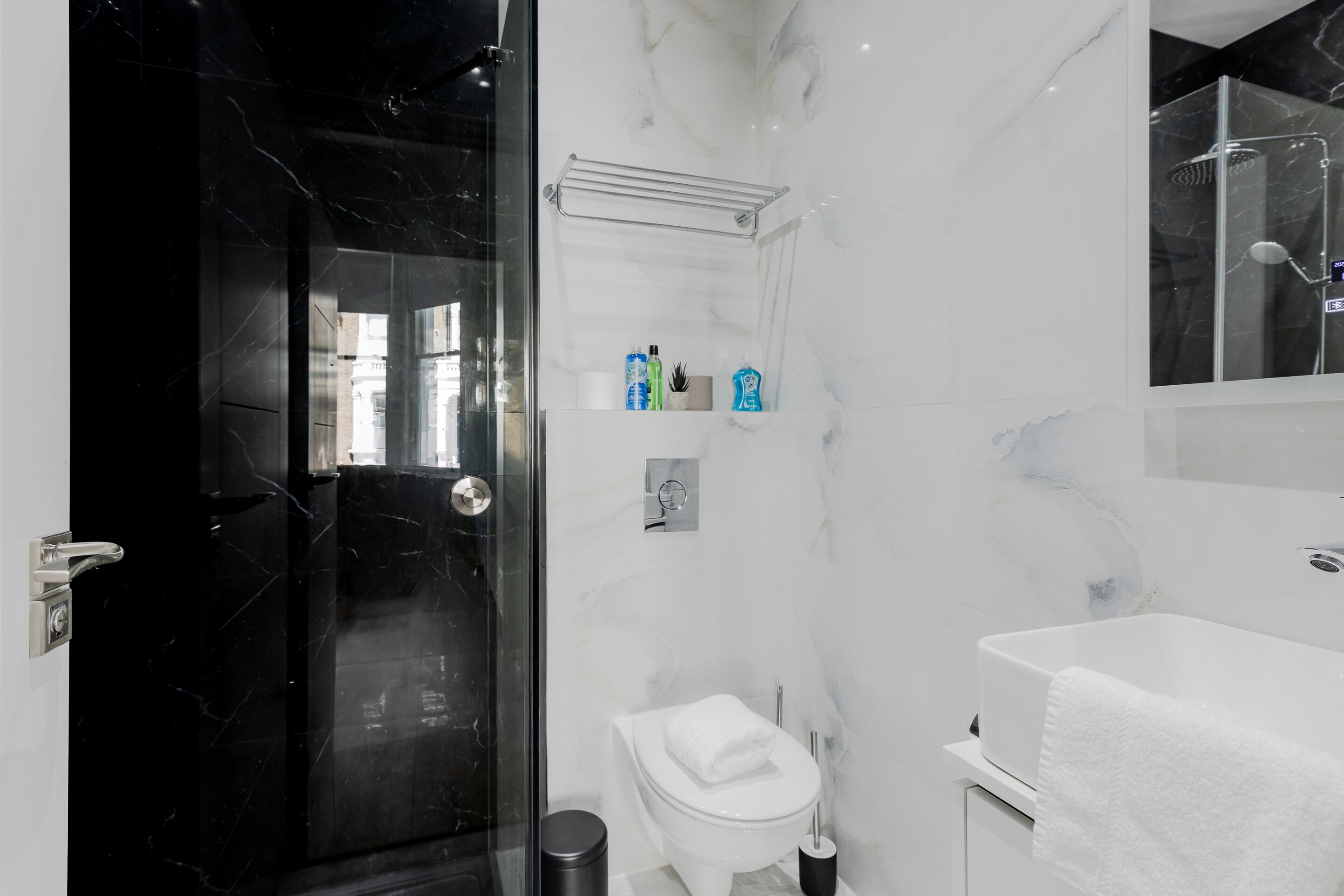 A modern bathroom with a glass shower enclosure, a white toilet, and a white bathtub.